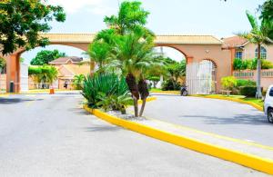 a street in front of a building with palm trees at Cozy Elegance 3 Bedroom Estate in Portmore