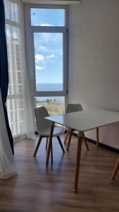 オデッサにあるApartment in Arkadiaの大きな窓のある客室で、テーブルと椅子が備わります。