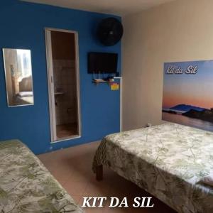 een slaapkamer met 2 bedden en een blauwe muur bij KIT DA SIL in Cabo Frio