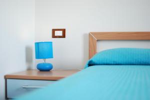 una cama azul con una lámpara azul sobre una mesa de madera en Tanca is Torus, en Teulada