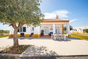 ein kleines weißes und gelbes Haus mit einem Tisch und Stühlen in der Unterkunft Herdade Monte Do Vale in Ferreira do Alentejo