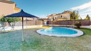 einen Pool mit Sonnenschirm und ein Haus in der Unterkunft Palmera by Oliva Nova in Oliva