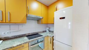 eine Küche mit gelben Schränken und einem weißen Kühlschrank in der Unterkunft Palmera by Oliva Nova in Oliva