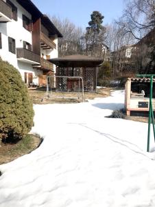un parque infantil frente a un edificio con nieve en el suelo en Villa Indipendente en Castello di Fiemme