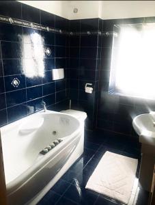 baño de azulejos azules con bañera y lavamanos en Villa Indipendente en Castello di Fiemme