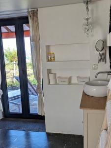 La salle de bains est pourvue d'un lavabo et d'une porte donnant sur une terrasse. dans l'établissement Casa Baleia Laranja Ocean-Front, à Cabeço Chão
