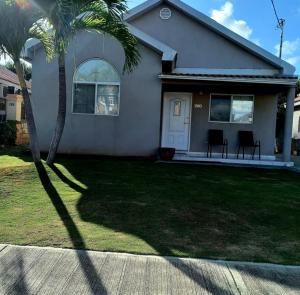 a house with a palm tree in the front yard at Mi Casa Comfort Estate in Portmore