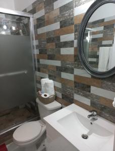 a bathroom with a toilet and a sink and a mirror at Mi Casa Comfort Estate in Portmore