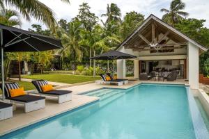 a swimming pool with chairs and umbrellas next to a house at Villa 25 in Port Vila