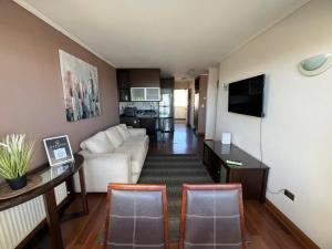 sala de estar con sofá blanco y TV en Reñaca Departamento Holiday Park 605 cómodo y buena ubicación familiar, en Viña del Mar