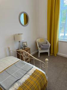 a bedroom with a bed and a chair and a mirror at Castle Brae Apartment in Stirling