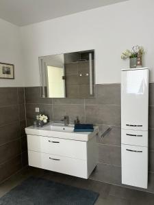 W łazience znajduje się biała umywalka i lustro. w obiekcie Ferienwohnung "Delftbrise" Emden w mieście Emden