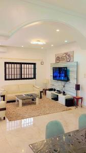 Luxe Villa في كوتونو: غرفة معيشة مع أريكة وتلفزيون بشاشة مسطحة