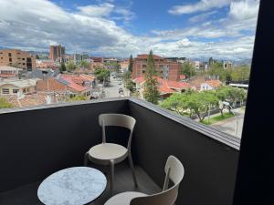 a balcony with two chairs and a view of a city at Rioné Hotel Boutique in Cuenca