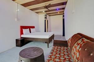 een slaapkamer met een bed en een bank in een kamer bij Super OYO Unnati Farm And Resort in Nūrpur