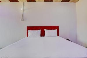 een wit bed met een rood hoofdeinde in een kamer bij Super OYO Unnati Farm And Resort in Nūrpur