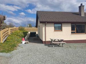 a house with a picnic table and a wooden fence at Self-catering in Portree in Portree
