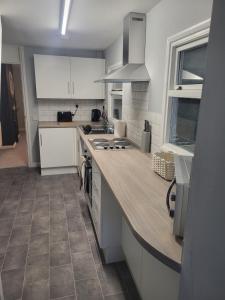 a kitchen with white cabinets and a wooden counter top at Cosy 2 Bedroom House in Kent +7 photos