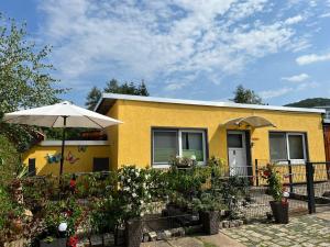 een geel huis met een paraplu en enkele planten bij Cosy holiday home in Wernigerode with large terrace in Hasserode