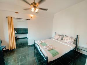 een slaapkamer met een bed en een plafondventilator bij Honeydew Suites and Villas by Goaround Homes in Vagator