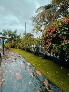 een tuin met een stenen loopbrug naast een hek bij Honeydew Suites and Villas by Goaround Homes in Vagator