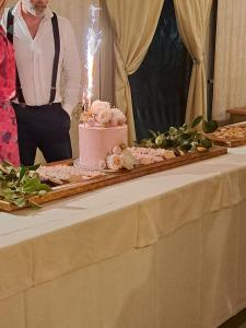 Ein Mann steht neben einem Tisch mit einem rosa Kuchen. in der Unterkunft Hotel Villa Cheli in Lucca + 208 Fotos