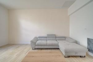 a living room with a gray couch in a white room at Les merveilles de la palmyre in Saint-Ciers-sur-Gironde