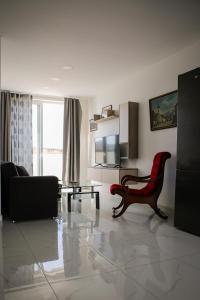 ein Wohnzimmer mit einem roten Stuhl und einem Sofa in der Unterkunft MB SEA VIEW Apartment in St Paul's Bay