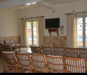 Hospedagem Sul de Minas Caxambu في كاكسامبو: غرفة بها مجموعة من الكراسي وتلفزيون بشاشة مسطحة