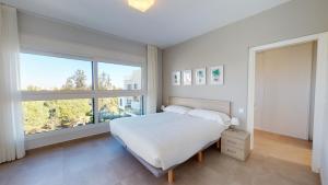 a bedroom with a white bed and a large window at Souvenir by ON Travel in Oliva +13 photos