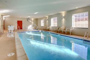 a large swimming pool in a room with chairs at Cobblestone Hotel & Suites - Salem in Salem