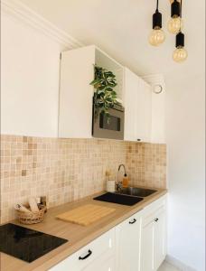 a kitchen with white cabinets and a sink at Appartement LUNA - lumineux, vue mer, à 50m de la plage, climatisé et parking inclus in Cagnes-sur-Mer