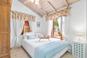 una camera con un letto bianco e una finestra di Villa Laurence Aruban Oasis Footsteps To Ocean a Savaneta
