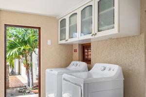 a laundry room with two washing machines and a window at Villa Laurence Aruban Oasis Footsteps To Ocean in Savaneta