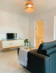 a living room with a couch and a tv at Appartement LUNA - lumineux, vue mer, à 50m de la plage, climatisé et parking inclus in Cagnes-sur-Mer