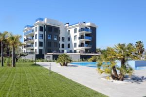 Un gran edificio de apartamentos con piscina y palmeras. en Leafy by ON Travel, en Oliva