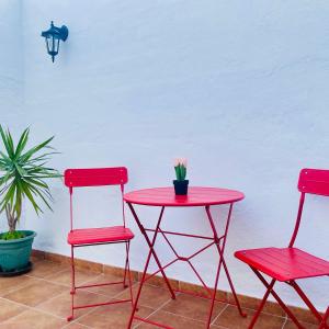 twee rode stoelen en een tafel met een bloem erop bij Patio de Los Barberos 3 in Valle de Abdalagís