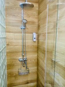 een douche in een badkamer met een houten muur bij Patio de Los Barberos 3 in Valle de Abdalagís