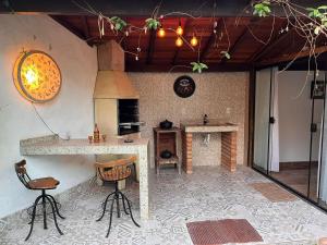 Il comprend une cuisine équipée d'une cuisinière et d'un comptoir avec des chaises. dans l'établissement JPK Guest House, à Tiradentes