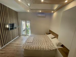 1 dormitorio con 1 cama y TV en Apartmani Vidikovac, en Prijepolje