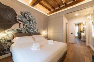 una camera da letto con un grande letto bianco e un dipinto sul muro di Palazzo 42 - Boutique Hotel & Suites a Pistoia