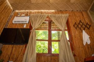 a room with a window with curtains and a television at Dumaguete Oasis Treehouse, near airport and mall, beside Magsaysay Elementary School in Dumaguete