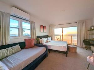 a bedroom with a bed and a couch and a window at OCEAN FRONT LUXE Manhattan Beach Strand in Manhattan Beach