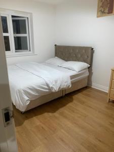 a bed with white sheets and a window in a room at 3 Bedroom Home Near Windsor Castle, Legoland, & Heathrow in Slough