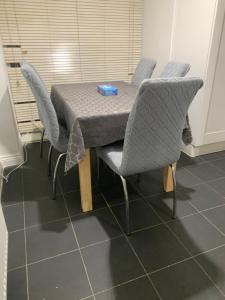 a table with chairs and a table cloth on it at 3 Bedroom Home Near Windsor Castle, Legoland, & Heathrow in Slough