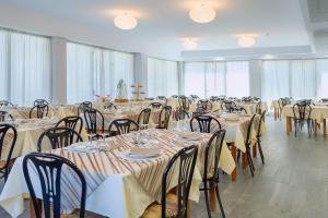 una grande sala banchetti con tavoli e sedie in una stanza di Hotel ROSE NUOVE a Rimini