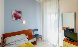 sypialnia z łóżkiem, biurkiem i telewizorem w obiekcie Hotel ROSE NUOVE w Rimini