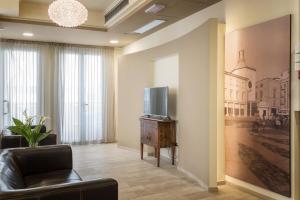 a living room with a couch and a tv on a wall at Hotel ROSE NUOVE in Rimini