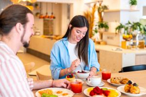 Ein Mann und eine Frau sitzen am Tisch und essen Essen. in der Unterkunft Hotel Estense in Gatteo a Mare