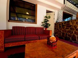 Sofá rojo en una habitación con pared de piedra en Valle verde, Hostel & camping en Urubamba